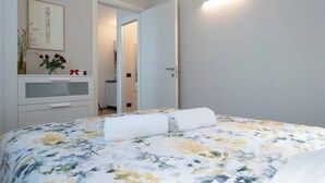 A bedroom with a bed, a dresser, a mirror, and a door leading to another room. - Elegant Panoramic Two-Room Apartment. Treiso Belvedere 1, Elegante Bilocale Panoramico. Treiso Belve... (Treiso)