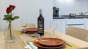 A dining table set with two plates, a wine bottle, and a vase with a single red rose. - Elegant Panoramic Two-Room Apartment. Treiso Belvedere 1, Elegante Bilocale Panoramico. Treiso Belve... (Treiso)