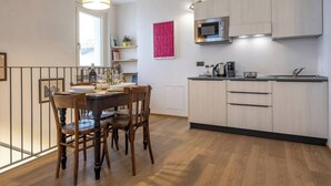 A modern kitchen with wooden cabinets, a microwave, and a dining area with a table and chairs. - Elegant Panoramic Two-room Apartment. Treiso Belvedere Elegance, Elegant Panoramic Two Bedroom Apartment. Treiso Belved... (Treiso)
