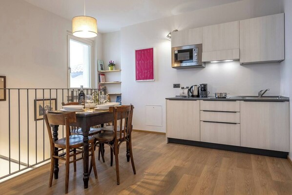 Una cocina moderna con armarios de madera, un microondas y una zona de comedor con mesa y sillas.