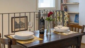 A dining table set with white plates, a wine bottle, and a vase with a red rose. - Elegant Panoramic Two-room Apartment. Treiso Belvedere Elegance, Elegant Panoramic Two Bedroom Apartment. Treiso Belved... (Treiso)