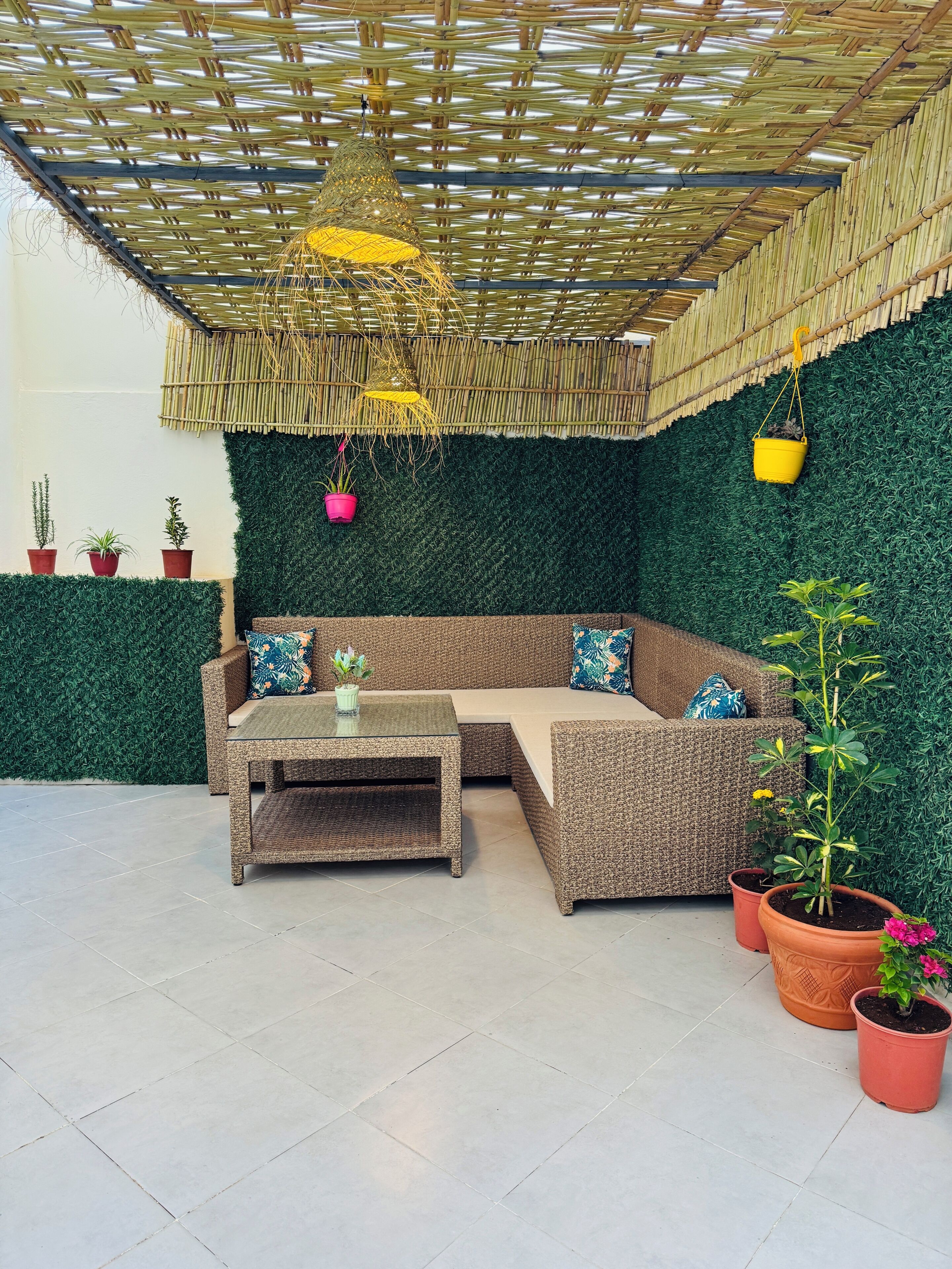 A corner seating area with a woven ceiling, green wall, and potted plants.