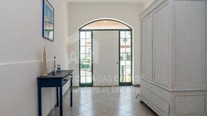 A hallway with a white door, a blue table, and a white cabinet. - Casa os Naias by ACasaDasCasas (Ericeira)