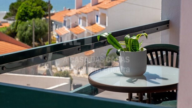 A balcony with a potted plant, a round table, and a chair. - Casa os Naias by ACasaDasCasas (Ericeira)