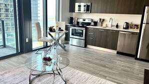 A modern kitchen with dark wood cabinets, stainless steel appliances, and a glass dining table with a white chair. - Lux apartment in Miami downtown (Miami)