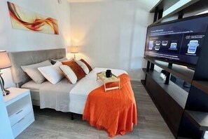 A modern hotel room with a bed, a nightstand, a TV, and a wall-mounted shelf. - Lux apartment in Miami downtown (Miami)