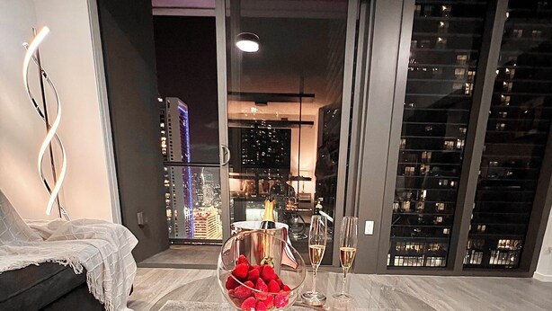 A modern living room with a glass coffee table, a sofa, and a view of the cityscape through large windows. - Lux apartment in Miami downtown (Miami)