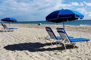 Une plage avec des parasols bleus et des chaises longues.