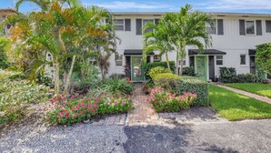 A two-story building with a paved driveway leading to a green door. - Magnificent Beach Townhome Steps from Atlantic Ave (Delray Beach)