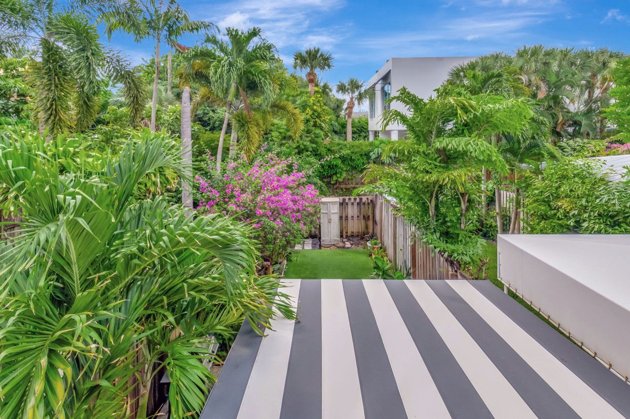 Un chemin mène à un bâtiment moderne, entouré d’une végétation luxuriante et de plantes tropicales.