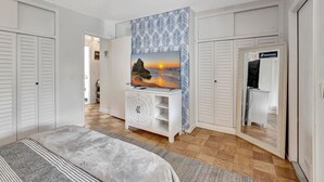 A bedroom with a bed, a dresser, a mirror, and a painting of a sunset. - Magnificent Beach Townhome Steps from Atlantic Ave (Delray Beach)