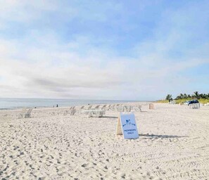 Una playa con un cartel que dice "SÓLO MIEMBROS" y filas de sillas de playa vacías.