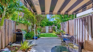 A covered patio area with a grill, outdoor seating, and a small garden. - Magnificent Beach Townhome Steps from Atlantic Ave (Delray Beach)