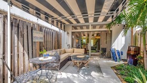 A covered patio with a sofa, chairs, and a table. - Magnificent Beach Townhome Steps from Atlantic Ave (Delray Beach)