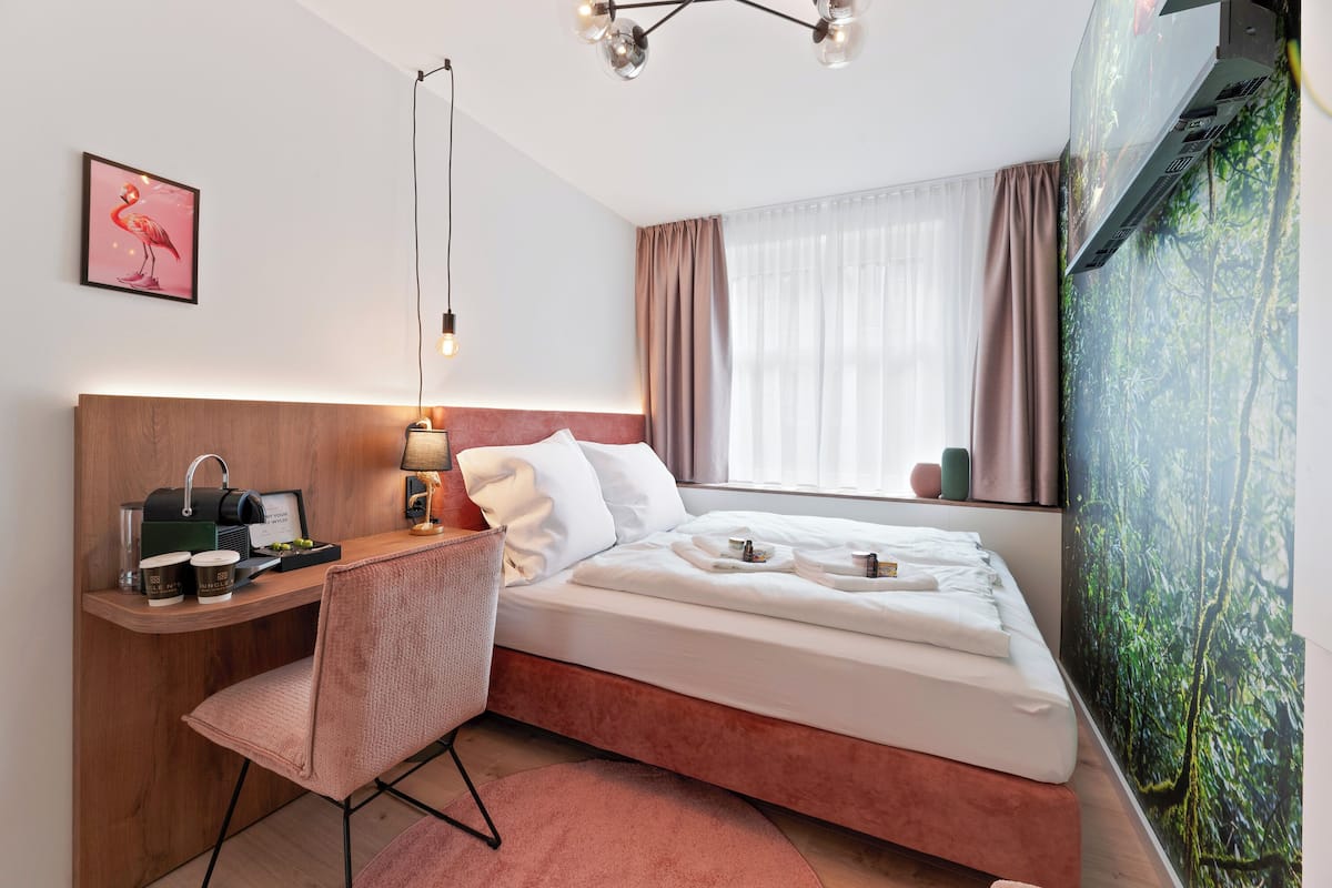 Une chambre d’hôtel avec un lit, un bureau et une chaise, une machine à café et un tableau au mur.