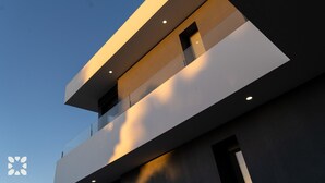 Un edificio moderno con techo plano, ventanas grandes y un balcón.