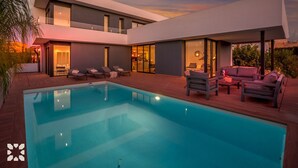 Una casa moderna con piscina, mobiliario exterior y ventanas amplias.