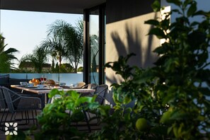 Un área de comedor al aire libre con una mesa dispuesta para dos personas, rodeada de sillas de mimbre.
