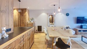 Een moderne keuken met houten kastjes, een centraal kookeiland en hangende lampen.