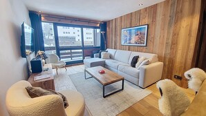 Een moderne woonkamer met een bank, fauteuils, een salontafel en een televisie.