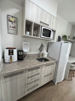 Uma cozinha moderna com micro-ondas embutido, cafeteira e geladeira.