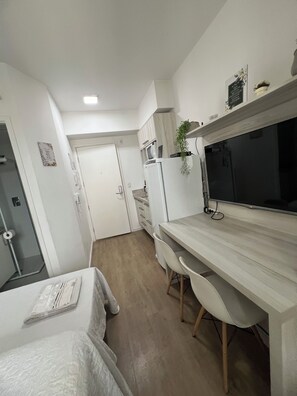 Una cocina compacta con microondas, refrigerador y un comedor con mesa y sillas.