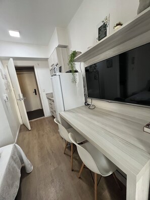 A modern kitchen with a wooden countertop, white cabinets, a built-in oven, and a black television.