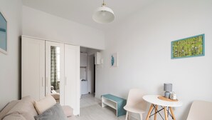 Una sala de estar moderna con un sofá, sillas, una mesita y una cocina al fondo.