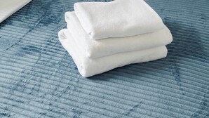 Una toalla blanca doblada cuidadosamente sobre una colcha azul con textura.
