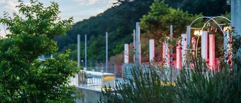 Un espace extérieur moderne doté d’un mur de verre, de structures métalliques et de verdure.