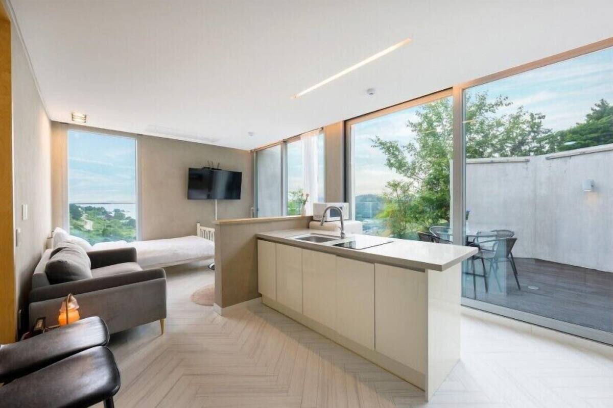 A modern apartment with a kitchen, dining area, and a large balcony with a view.