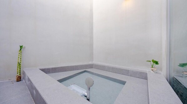 A modern bathroom with a built-in bathtub, a small window, and a potted plant. - west side (Tongyeong)