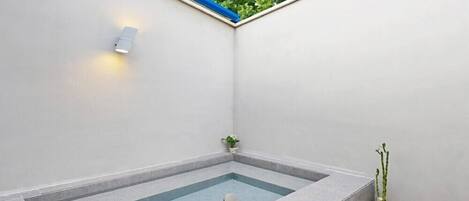 Une petite salle de bain moderne avec une baignoire intégrée, un luminaire fixé au mur et une plante en pot.