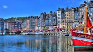 Una orilla con edificios históricos y un barco rojo amarrado en el muelle.