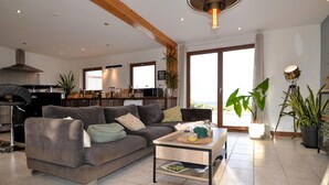 A modern living room with a grey sofa, a coffee table, and a kitchen in the background. - Amazing home in Mejannes le Clap (Mejannes le Clap)