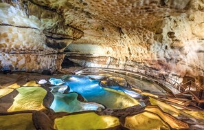 A cave interior with a natural pool and stalactites.
