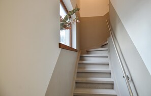 Una escalera con barandilla, una ventana con planta y una puerta en la parte superior.