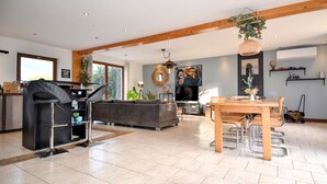 A spacious living area with a sofa, a dining table with chairs, a kitchen area with a grill, and a large window providing natural light. - Amazing home in Mejannes le Clap (Mejannes le Clap)