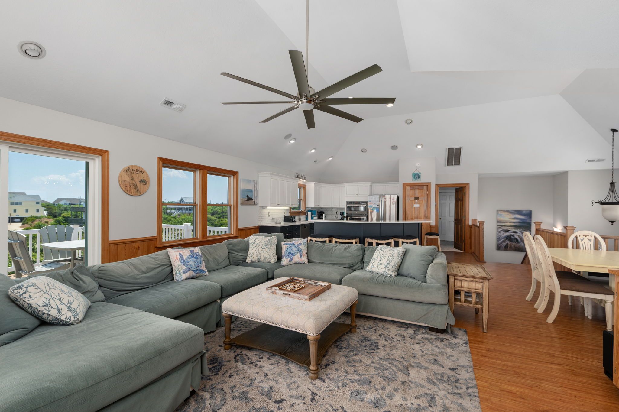A modern living room with a large sectional sofa, a coffee table, and a dining area with wooden chairs.