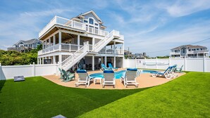 Una casa de dos pisos con un balcón grande, una piscina y un césped bien cuidado.