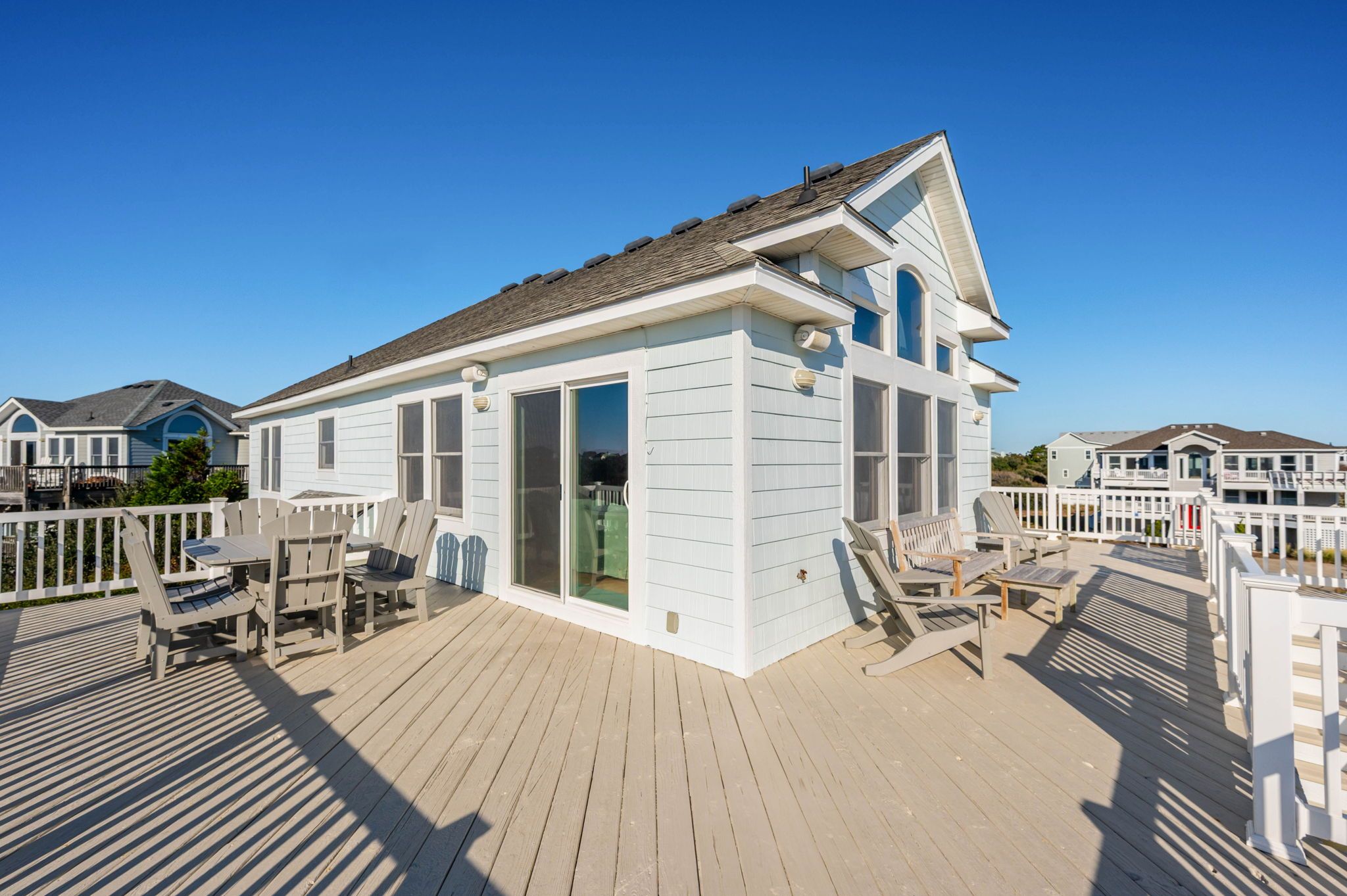 A beach house with a covered patio, outdoor seating, and a view of the ocean.
