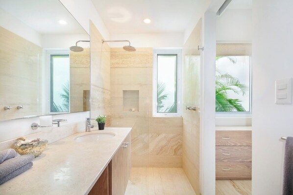 Un baño moderno con un espejo grande, ducha y ventana.