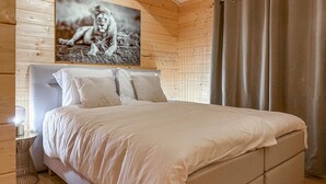 A bedroom with a wooden headboard, a large bed with white bedding, and a framed picture of a lion on the wall. - 3 bedroom lovely home in Meijel (Meijel)