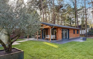 Una cabaña de madera con un patio, rodeada de árboles.
