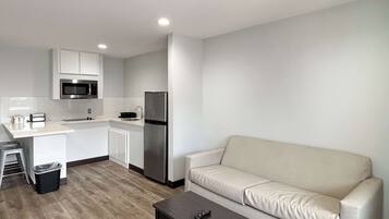 Un espacio habitable pequeño con kitchenette, un sofá y una mesita.