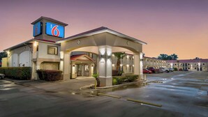 A motel with a prominent '6' sign, a covered entrance, and a parking lot. - Studio 6 Sulphur, LA (Sulphur)