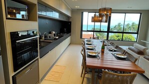A modern kitchen with built-in appliances and a dining area with a view of the ocean.