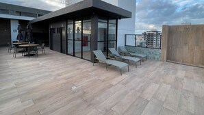 A rooftop terrace with outdoor seating and a glass-enclosed area.