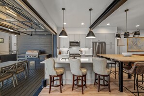 A modern kitchen with stainless steel appliances, a central island with bar stools, and pendant lighting. - High Country Howdy, AC! Indoor/Outdoor Kitchen Space, Private Hot Tub,  Athletic Club Access! (Steamboat Springs)