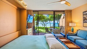Ein Hotelzimmer mit Bett, einer Sitzecke, einem Fernseher und Blick auf den Ozean.